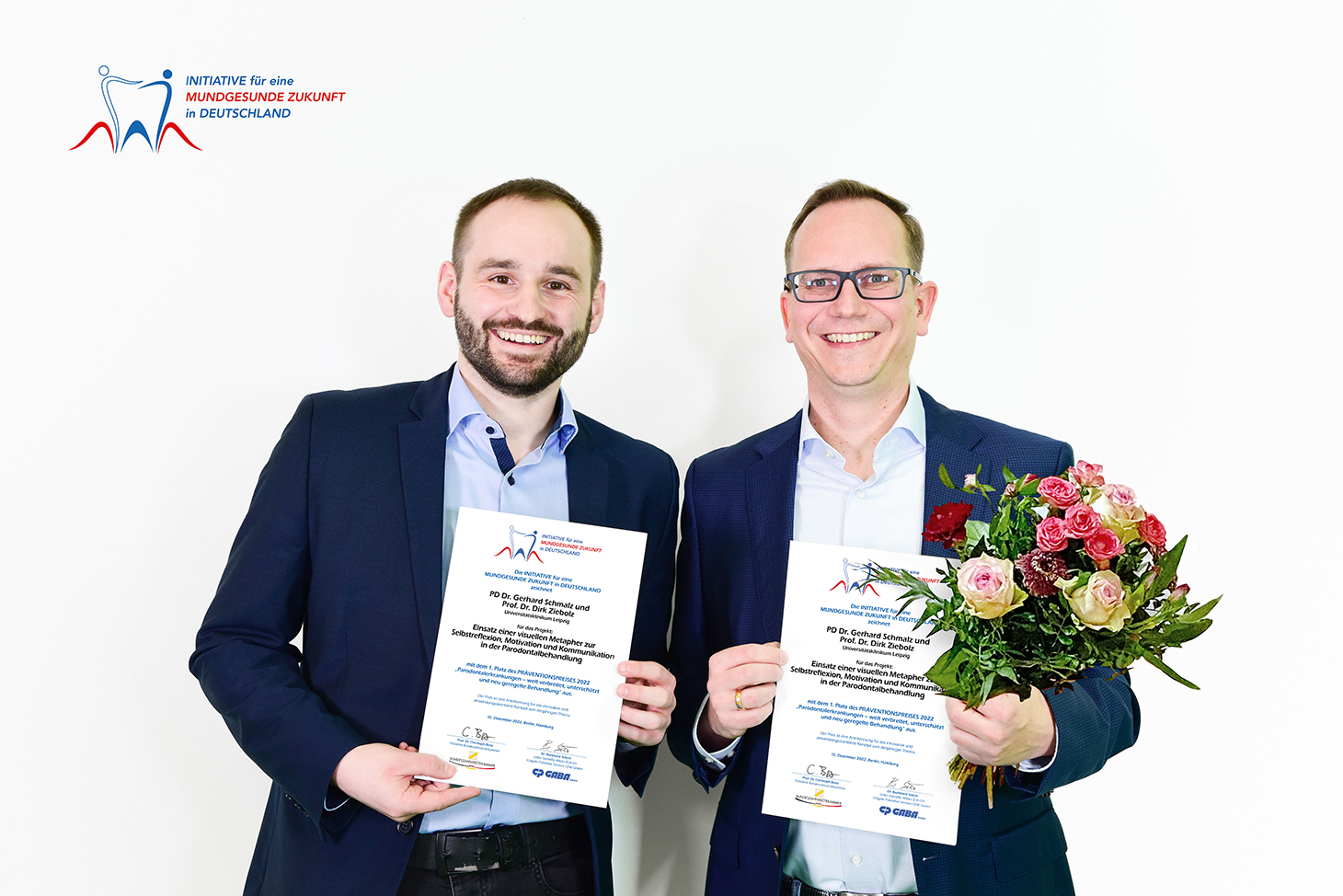 zwei Männer mit Strauss und Urkunde